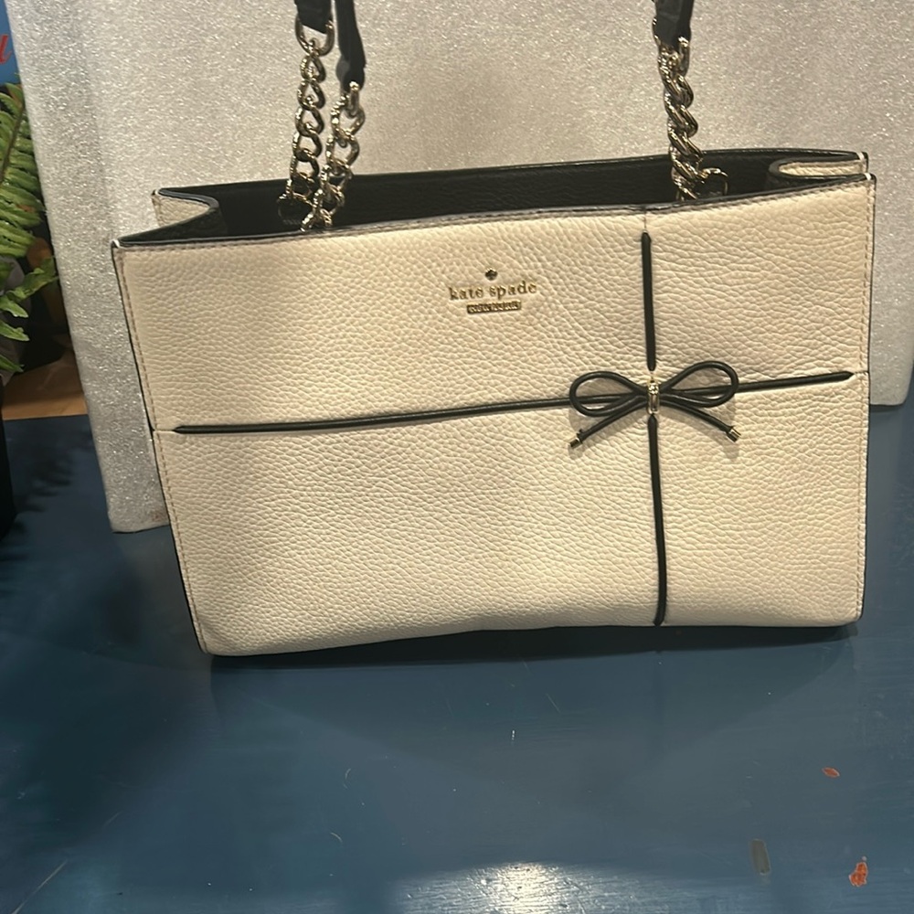Kate spade off white rectangular purse with black bow.